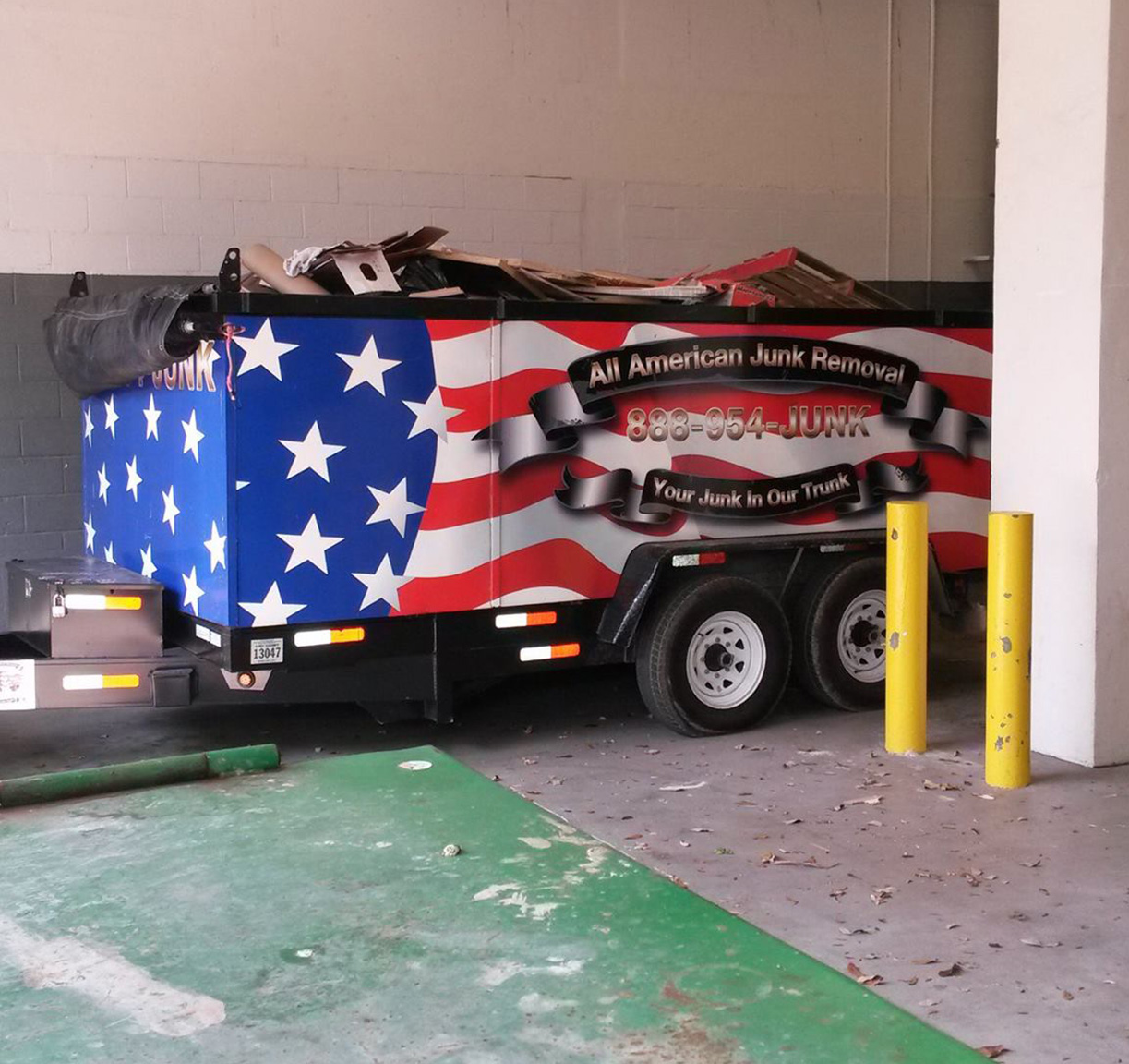 A garbage truck in a garage proudly displaying an American flag.